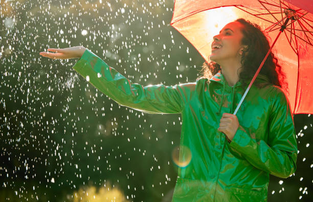 shot of a beautiful young woman having fun in the rain - rain woman sun stockfoto's en -beelden