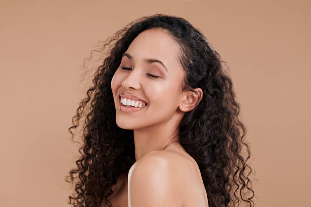 Shot of a beautiful young woman laughing and posing against a brown background stock photo
