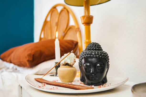 Shot of a buddha ornament, incense stick and candle in an empty bedroom during the day Invest in your space buddha statue home decor stock pictures, royalty-free photos & images