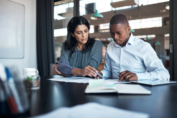 Shot of a businessman and businesswoman going over paperwork in a modern office stock photo