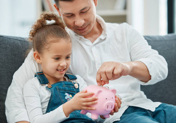 Shot of a father teaching his daughter to save in a piggybank Teaching her the value of money allowance stock pictures, royalty-free photos & images