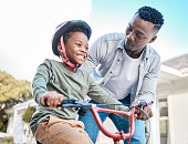 istock Shot of a father teaching his son to ride a bicycle outdoors 1338857220