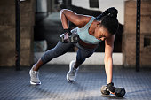 istock Shot of a fit young woman working out with dumbbells at the gym 1359197348