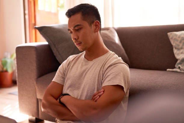 Shot of a handsome young man sitting alone in his living room and looking contemplative while working from home I need to really think about this think stock pictures, royalty-free photos & images