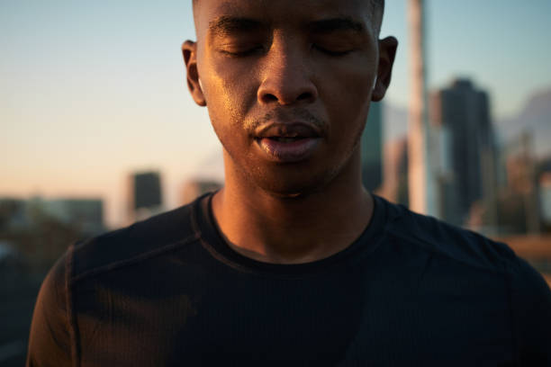 Shot of a handsome young man taking a moment to catch his breath after a morning run in the city stock photo
