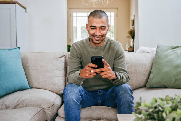 Shot of a handsome young man using his smartphone to send a text message stock photo