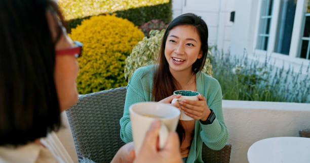 Shot of a mother and daughter having coffee outside on the verandah stock photo