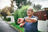 istock Shot of a senior man standing alone outside and checking his watch after going for a run 1352619756