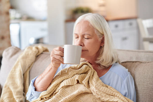 Shot of a senior woman drinking tea while feeling sick at home stock photo