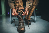 istock Shot of a soldier tying his boot shoelaces in the dorms of a military academy 1348968273