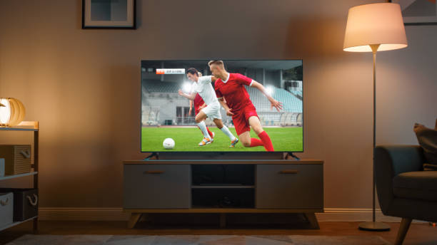 shot of a tv with soccer match. cozy evening living room with a chair and lamps turned on at home. - soccer night imagens e fotografias de stock