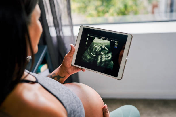 Shot of a woman looking at a sonogram on a tablet at home stock photo