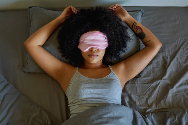 Shot of a woman wearing a sleeping mask while lying on her bed I'm in do not disturb mode eye mask stock pictures, royalty-free photos & images