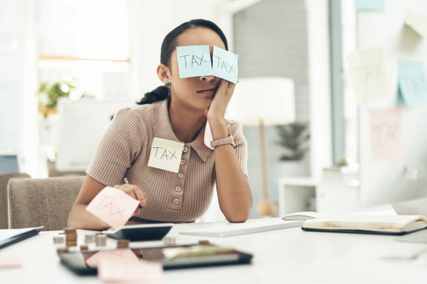Shot of a young businesswoman covered in sticky notes while working on her taxes in an office Tax is such a deathly dull topic filing documents stock pictures, royalty-free photos & images