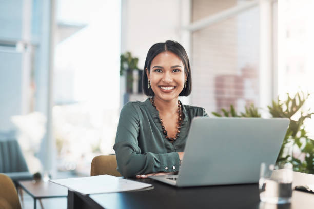 Shot of a young businesswoman using a laptop in a modern office stock photo