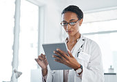 istock Shot of a young doctor using her digital tablet at work 1357522266