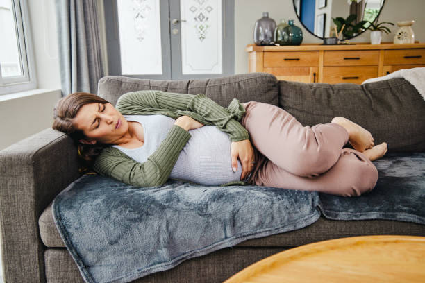 Shot of a young expecting mother experiencing contractions at home stock photo