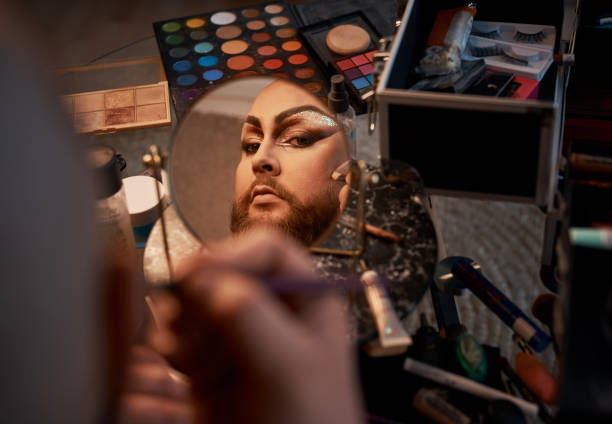 Shot of a young man applying theatrical makeup to his face in a studio stock photo
