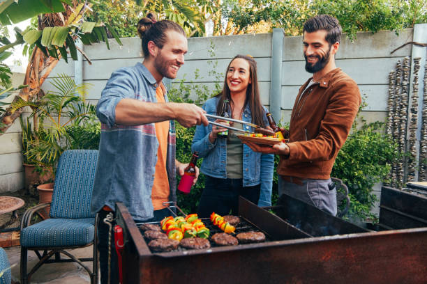 Shot of a young man serving up grilled food to his friend stock photo