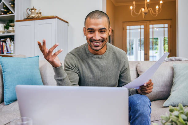 Shot of a young man working from home using his laptop to conduct a video call stock photo
