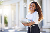 istock Shot of a young woman carrying her schoolbooks outside at college 1365611259