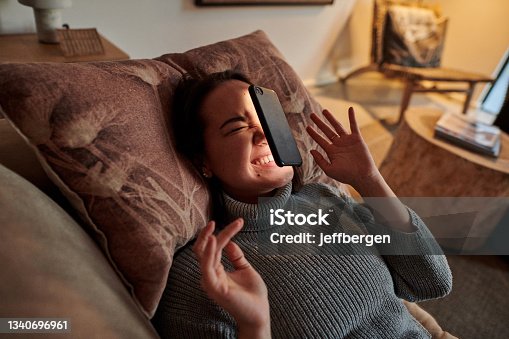 istock Shot of a young woman lying on the couch after her phone fell on her face 1340696961