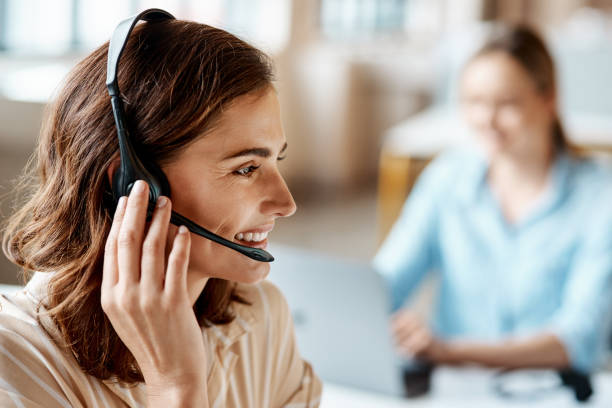Shot of a young woman using a headset in a modern office stock photo