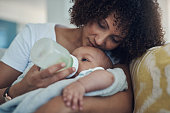 istock Shot of an adorable baby girl being bottle fed by her mother on the sofa at home 1323109253