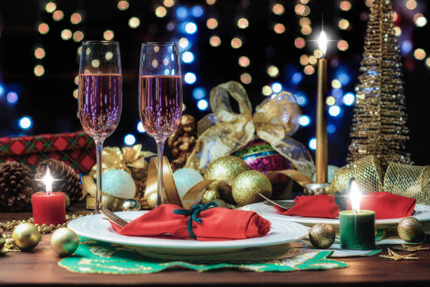 Shot of Champagne flutes in table for two over golden holiday background. Christmas and New Year celebration stock photo
