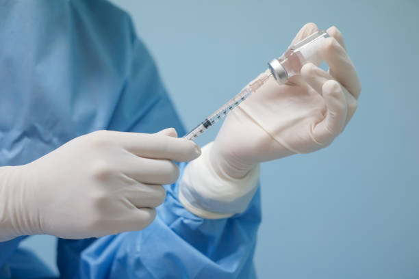 shot of doctor's hands in  latex gloves showing the vaccine vial and syringe filled with medicine. stock photo