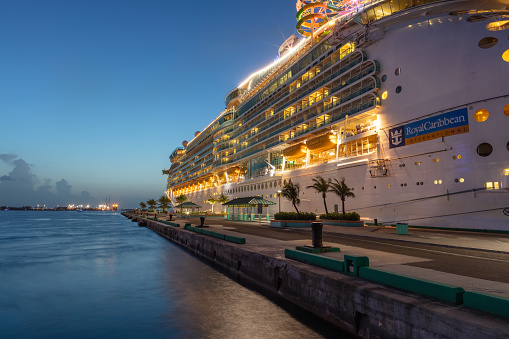 Nassau, Bahamas - July 13, 2019: Shot of Mariner of the Seas at Prince George Wharf at sunset. Blue hour. Gorgeous light reflections in the water in the foreground. Clear blue sky in the background.