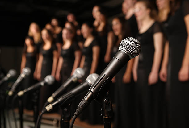 Shot of microphones with choir in the background A Vocal Music Performance singing stock pictures, royalty-free photos & images