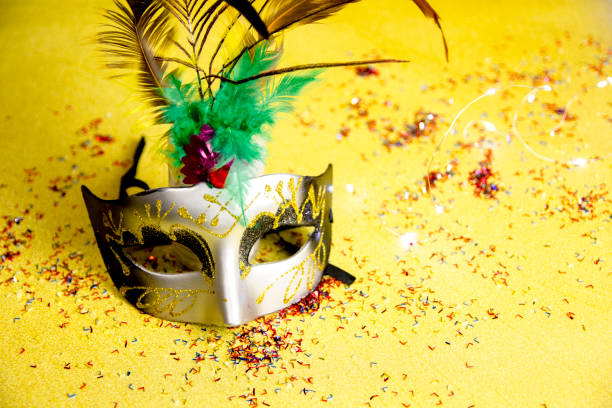Shot of one Venetian masks on a gold background with sparkling lights and cofetti. Concept of elegant Carnival and Carnival in Venice. Copy Space. stock photo
