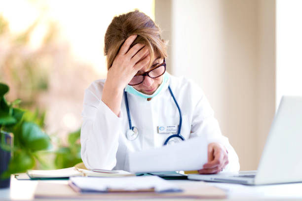 Shot of stressed female doctor sitting at doctor's office and working stock photo