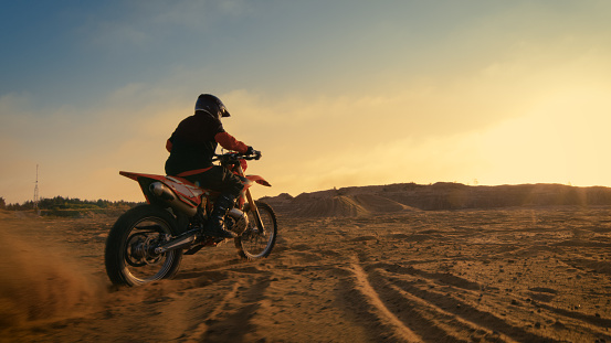 Shot of the Professional Motocross Driver Riding on His FMX Motorcycle on the Extreme Off-Road Terrain Track.