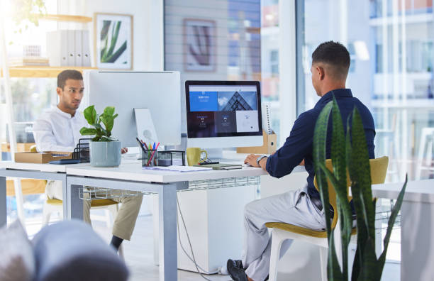 Shot of two men working on their computers in a modern office You know how to reach us web design stock pictures, royalty-free photos & images