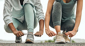 istock Shot of two unrecognizable people tying their shoelaces before a run 1372333221