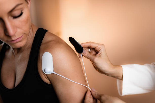 Shoulder Physical Therapy with TENS Electrode Pads, Transcutaneous Electrical Nerve Stimulation Shoulder Physical Therapy with TENS Electrode Pads, Transcutaneous Electrical Nerve Stimulation. Therapist Positioning Electrodes onto Patient's Shoulder electrode stock pictures, royalty-free photos & images