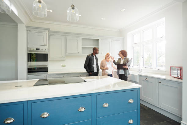 showhome viewing a saleswoman or estate agent shows a couple around a home with new kitchen model house stock pictures, royalty-free photos & images