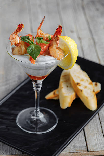 shrimp in a sauce with lemon on a wooden table stock photo