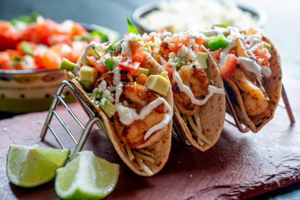 Shrimp Street Tacos Shrimp Street Tacos with all the Trimmings like Avocado, Sour Cream and Cotilla Cheese on a Rustic Slate to be Served in a Trendy Restaurant shrimp seafood stock pictures, royalty-free photos & images