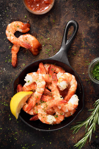 Shrimps in a skillet Tiger shrimps in a skillet cooking pan with cocktail sauce and seasoning shrimp cocktail stock pictures, royalty-free photos & images