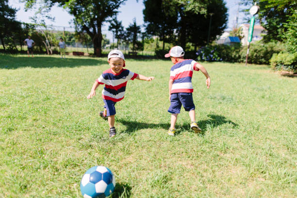братья и сестры играют в футбол в общественном парке - july 4 стоковые фото и изображения