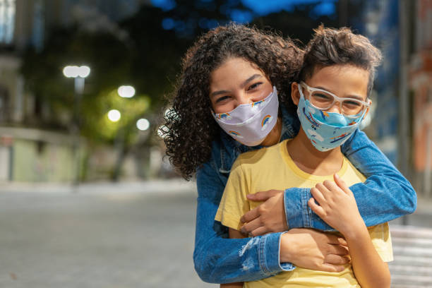 siblings with n95 respiratory mask outdoors at night - máscara de proteção imagens e fotografias de stock