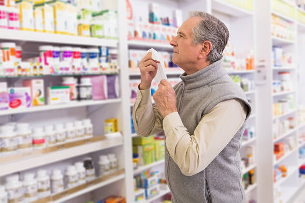 Sick customer holding a tissue Sick customer holding a tissue in the pharmacy allergy medicine stock pictures, royalty-free photos & images