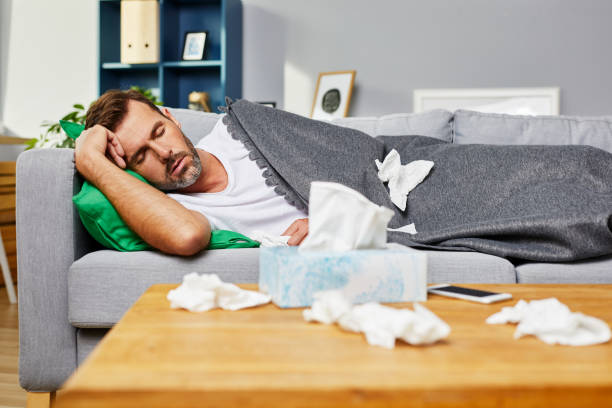 pria sakit berbaring di sofa dan tidur di rumah - sleep flu potret stok, foto, & gambar bebas royalti