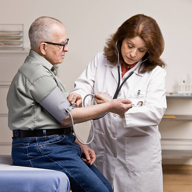 Sick patient having blood pressure taken by doctor during checkup stock photo