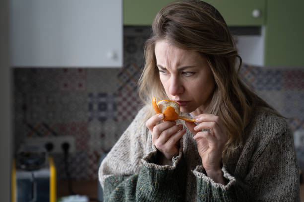 Sick woman trying to sense smell of fresh tangerine orange, has symptoms of Covid-19, corona virus Sick woman trying to sense smell of fresh tangerine orange, has symptoms of Covid-19, corona virus infection - loss of smell and taste, standing at home. One of the main signs of the disease. scented stock pictures, royalty-free photos & images
