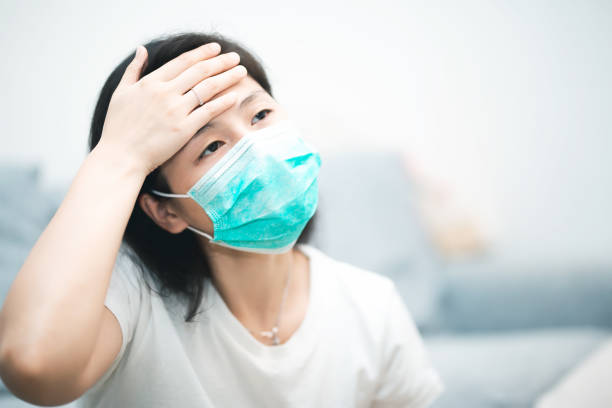 Sick young woman wearing mask at home stock photo