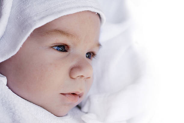 Side portrait of a beautiful baby covered with white towel